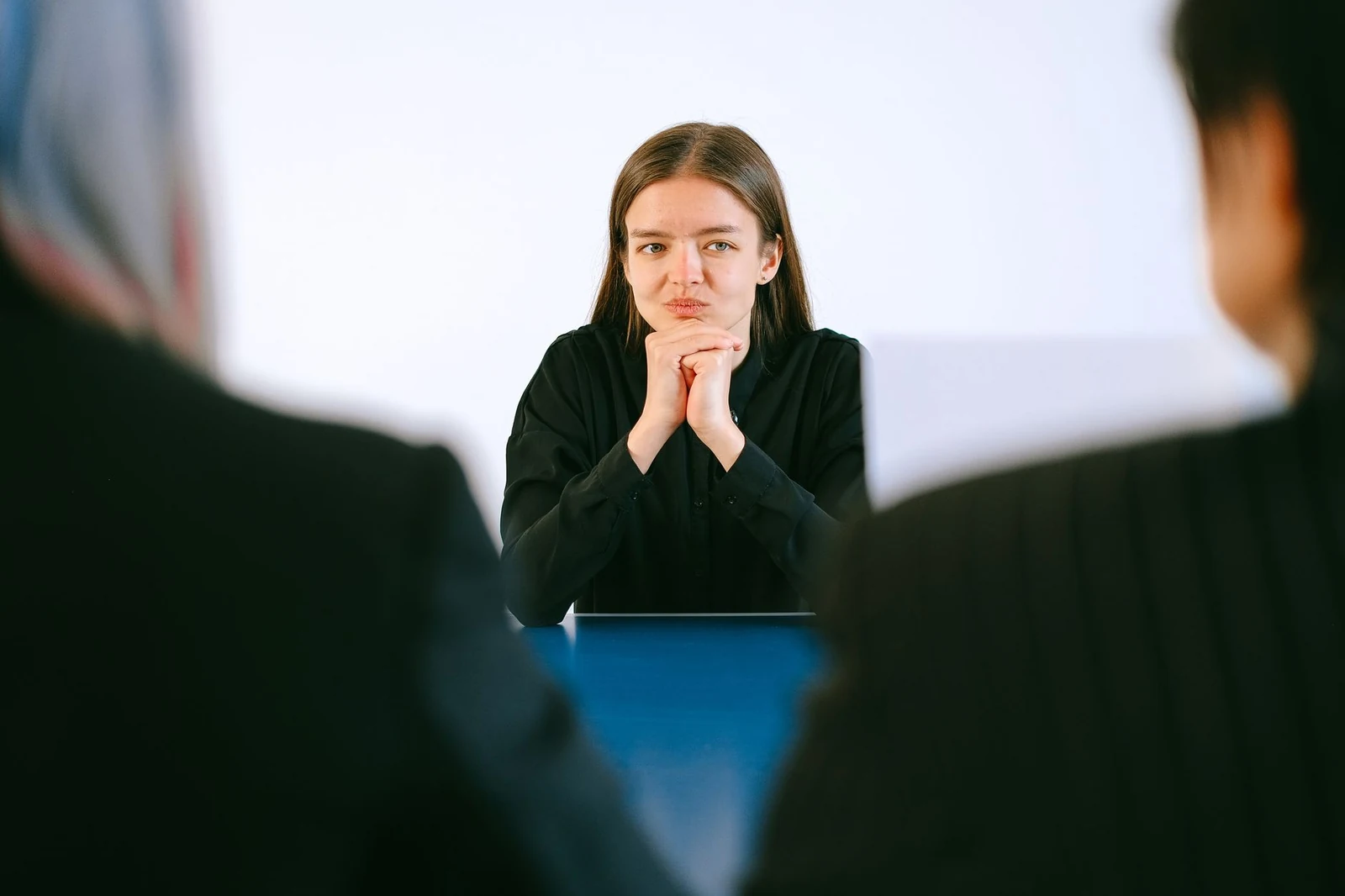 Interview conversation during the hiring process A candidate in an interview answering questions from two interviewers at an office table
