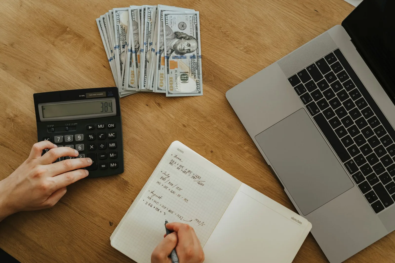 A person working through hiring expenses with a calculator and laptop