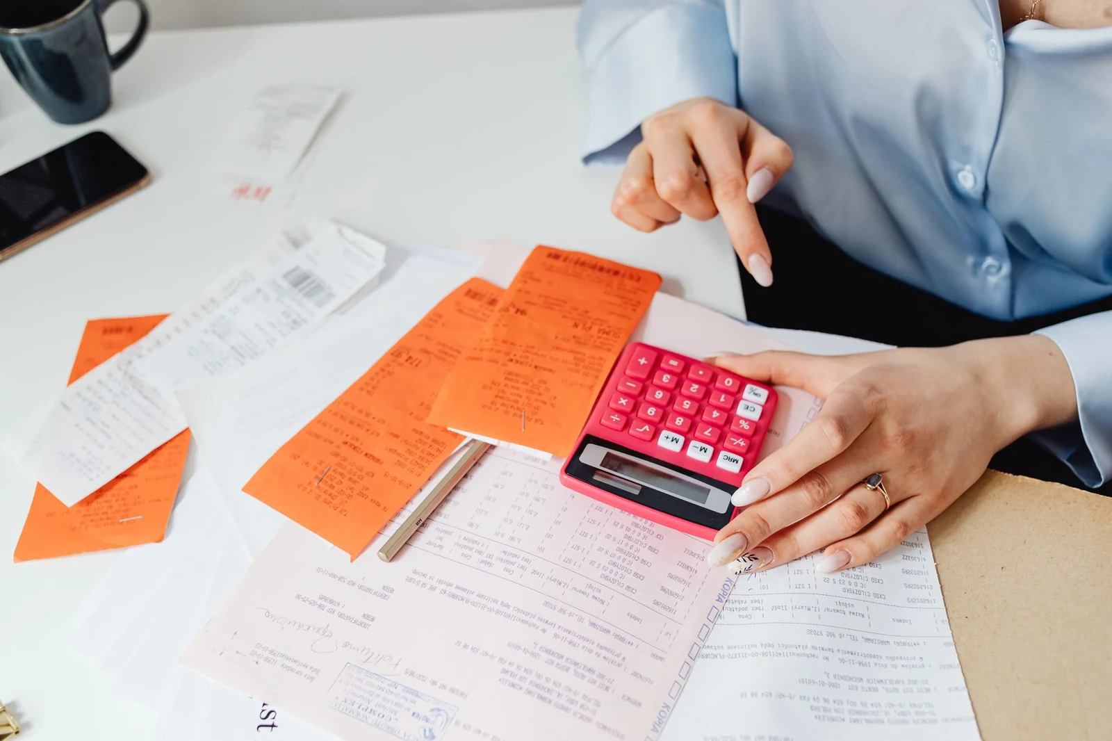 Calculator beside printed invoices used to add up recruiting costs