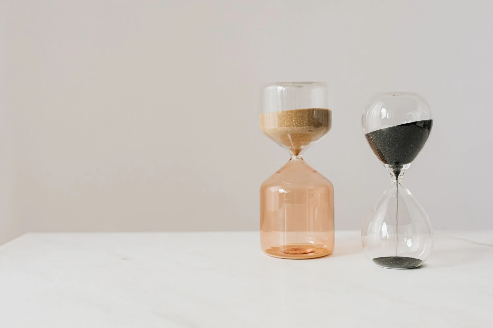 An hourglass on a desk beside a laptop