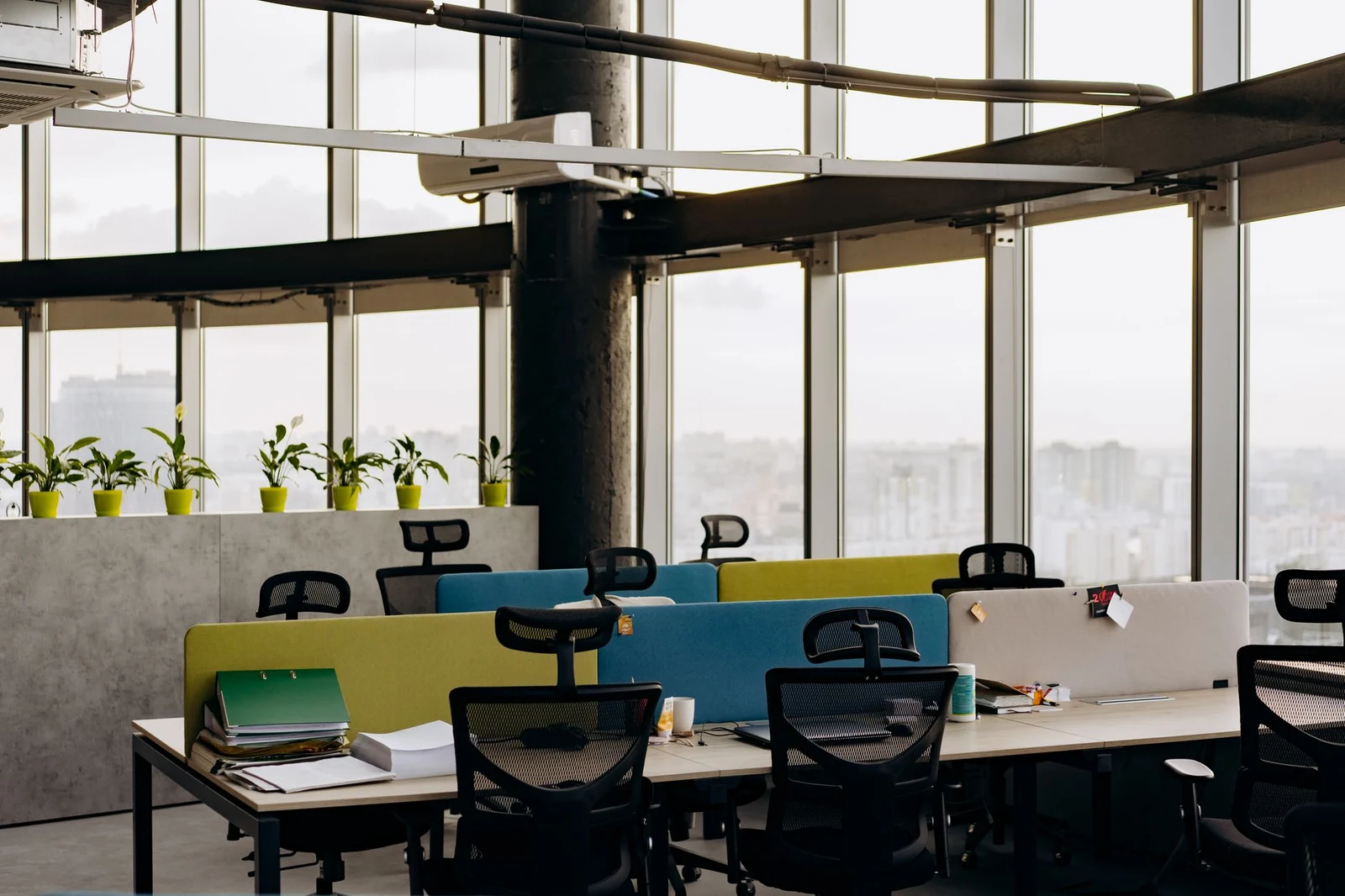 An empty chair at an unoccupied desk beside an office window