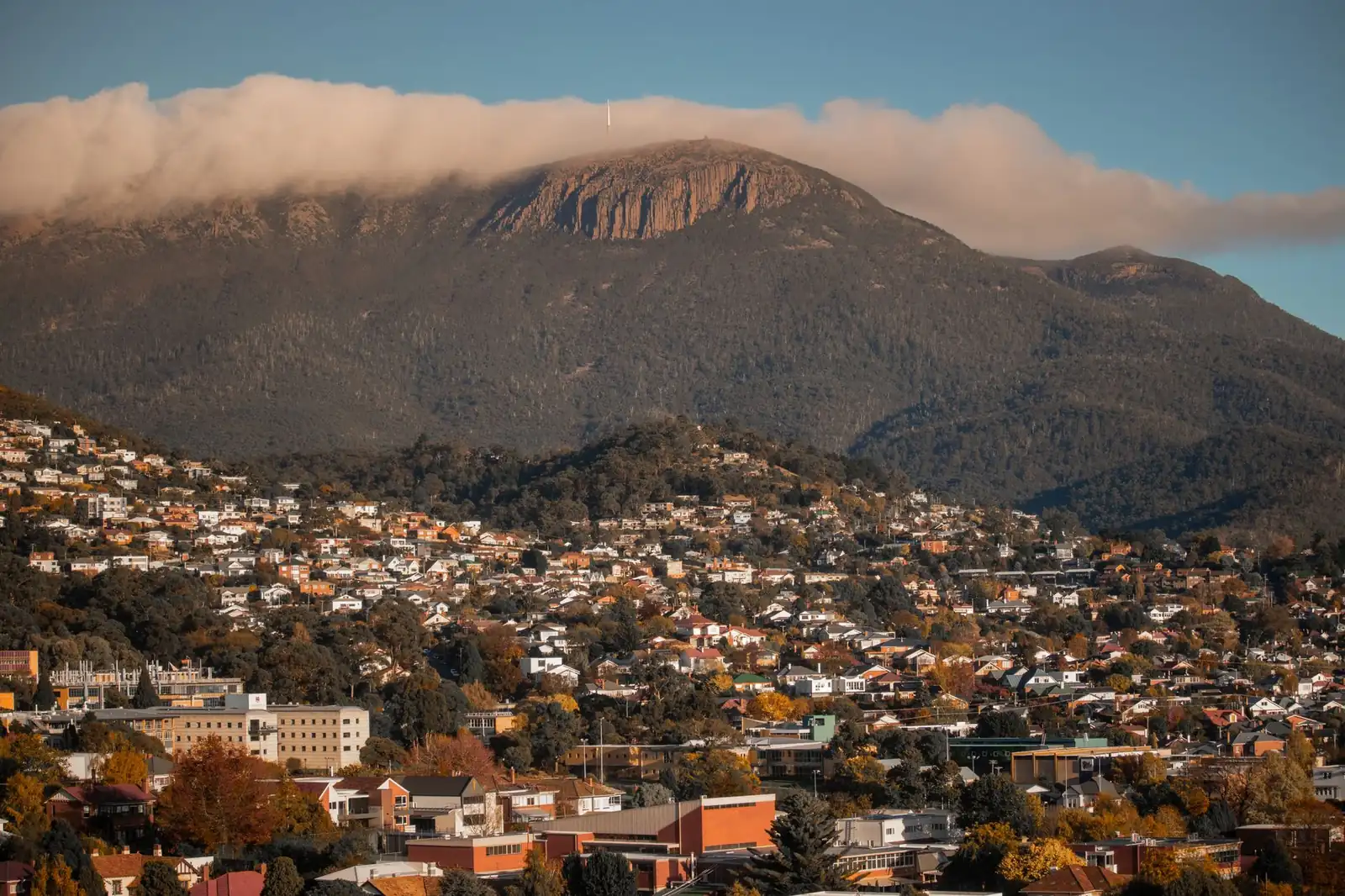Row of single-family homes with foothills behind them at golden hour