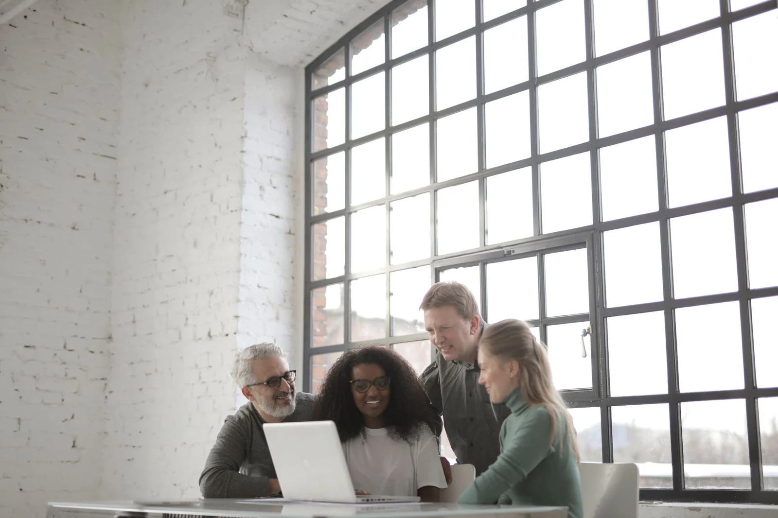 Small group standing around a laptop in a bright office
