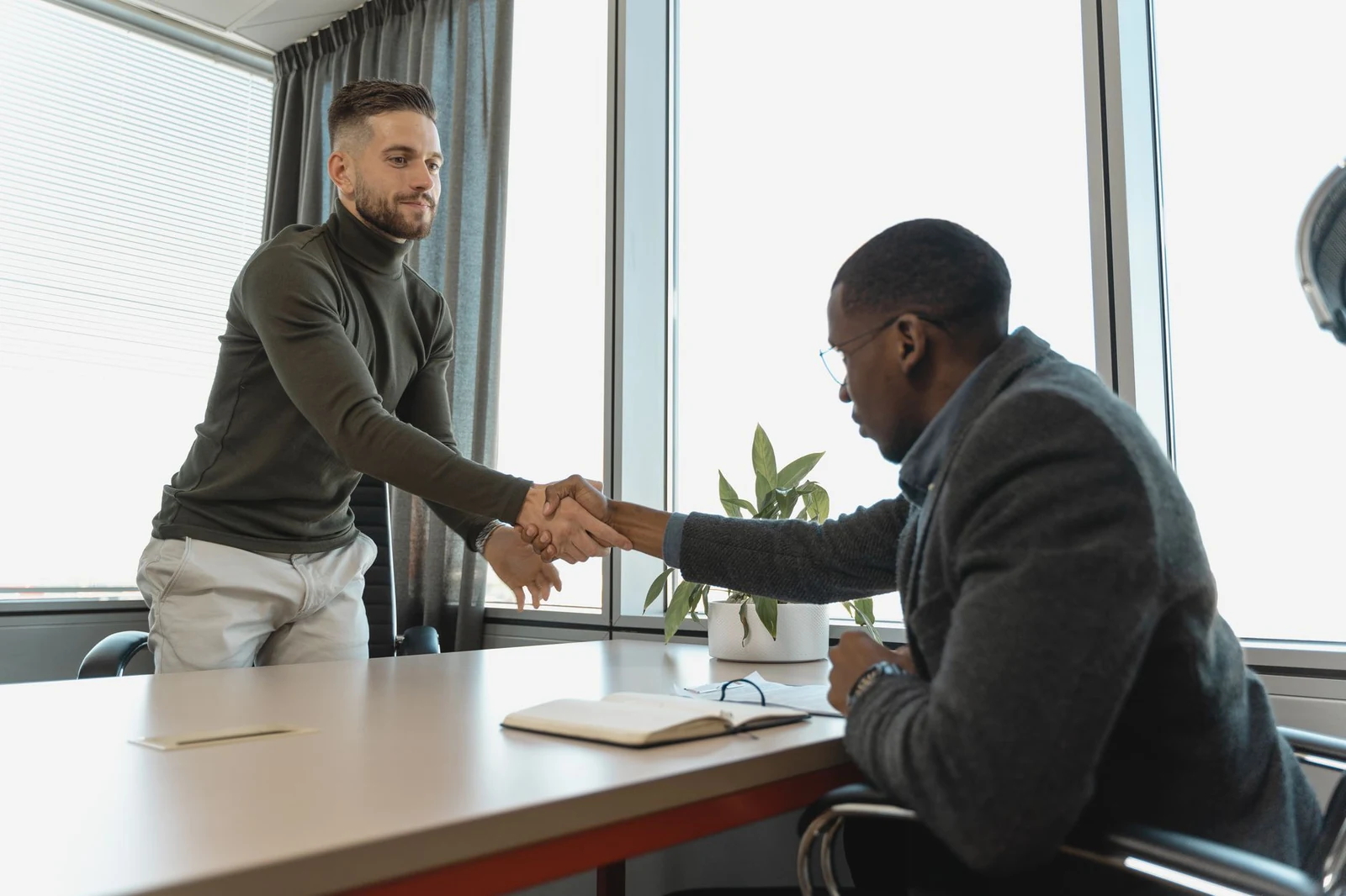 Hiring manager and candidate shaking hands in a bright office