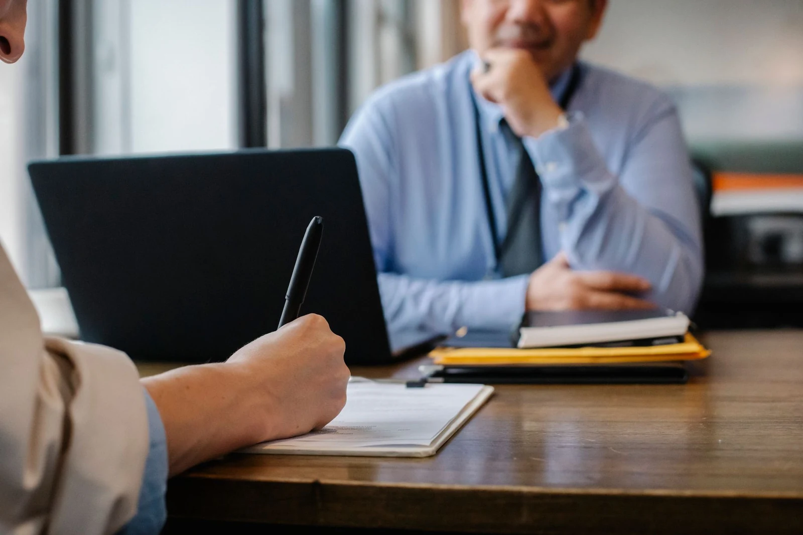 Two people reviewing printed resumes together at a meeting table