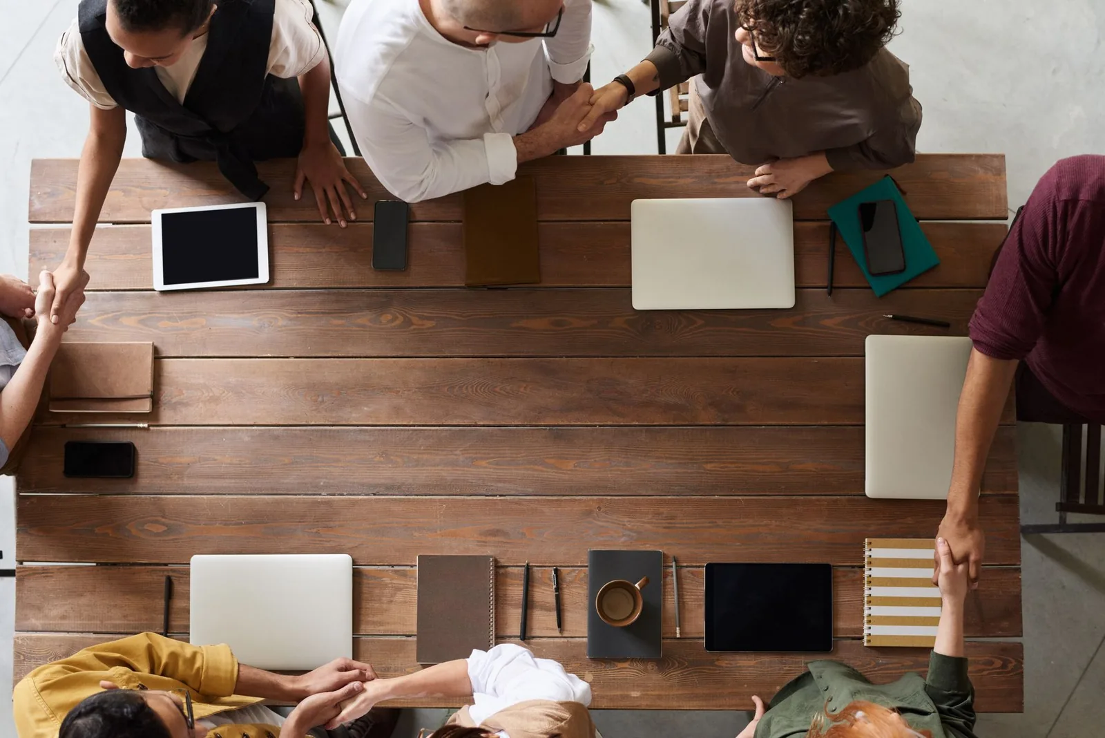 Two professionals shaking hands across a table in a bright office