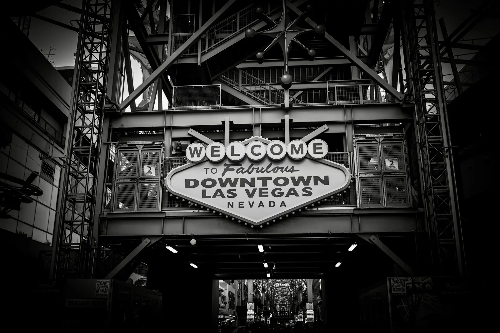 Black and white photo of the Welcome to Fabulous Downtown Las Vegas Nevada sign mounted on a steel structure at the entrance to a covered street