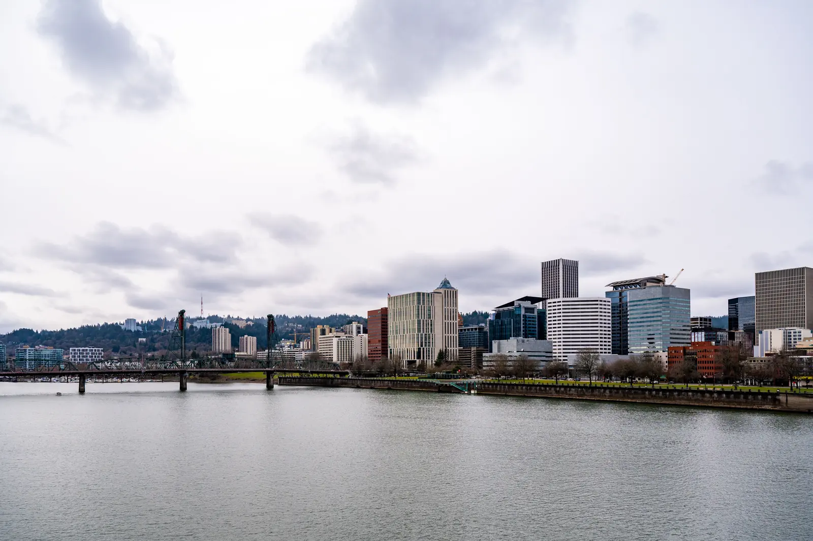 Portland, Oregon waterfront skyline Downtown Portland, Oregon office towers lining the Willamette River waterfront on an overcast day, with a steel lift bridge on the left